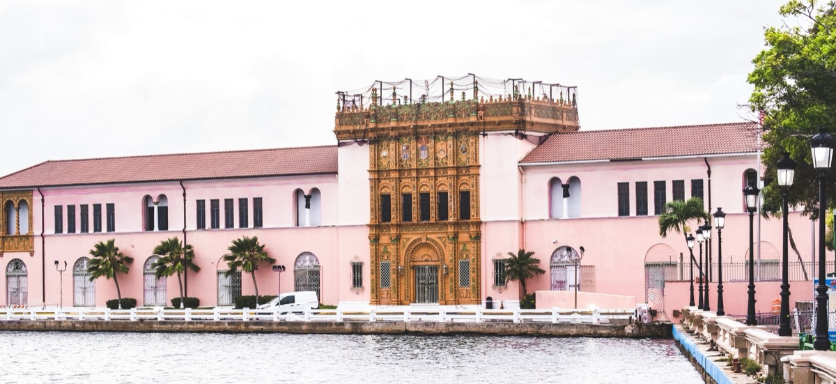 Una foto di un'antica costruzione bahamana con un gruppo di membri della Royal Family in fondo.