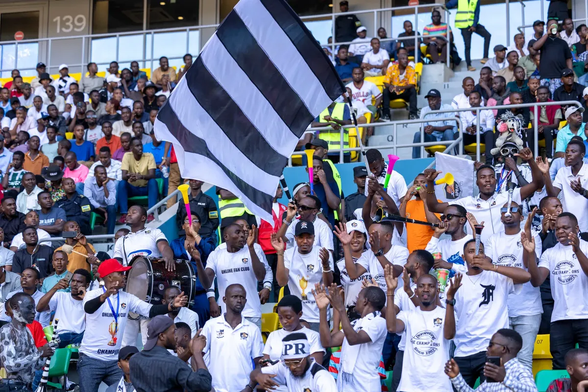 Lively crowd of sports fans cheering at a football match, showcasing Rwandan team spirit.