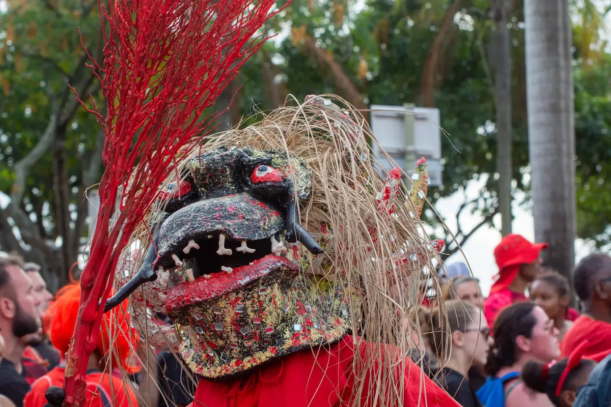A vibrant festival scene with people in traditional costumes, featuring a unique mask.